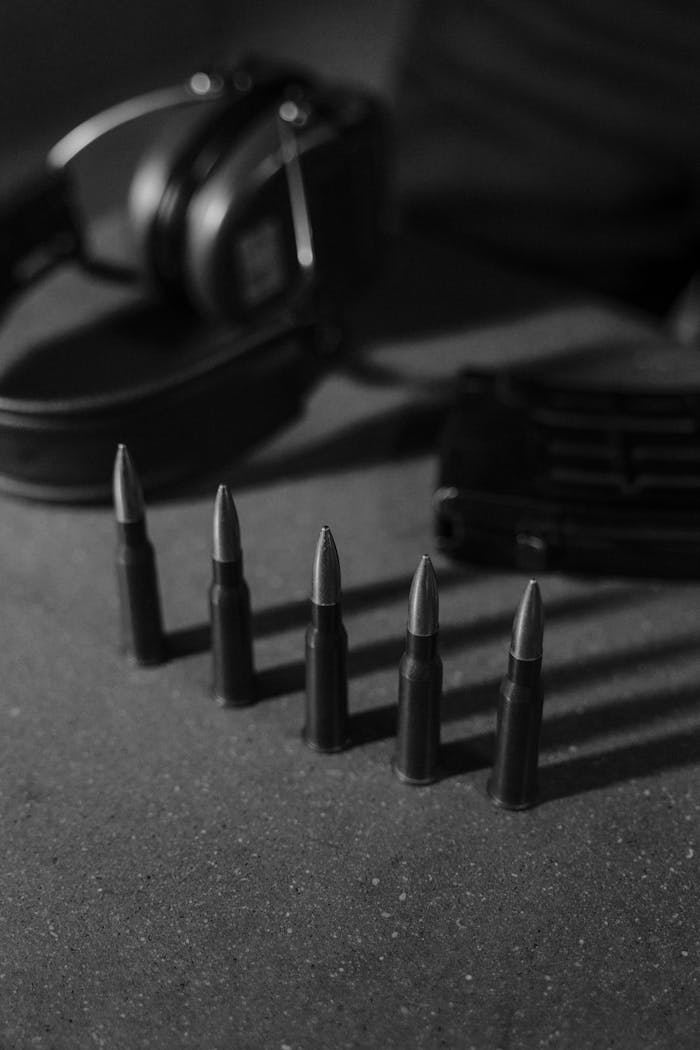 heros-img Monochrome image of bullets, headphones, and magazine on a concrete surface.